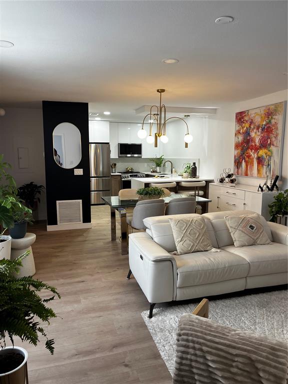 An open-concept living and dining area features a modern kitchen, light wood flooring, and furniture — 110 WINDTREE LANE UNIT 202, WINTER GARDEN, FL