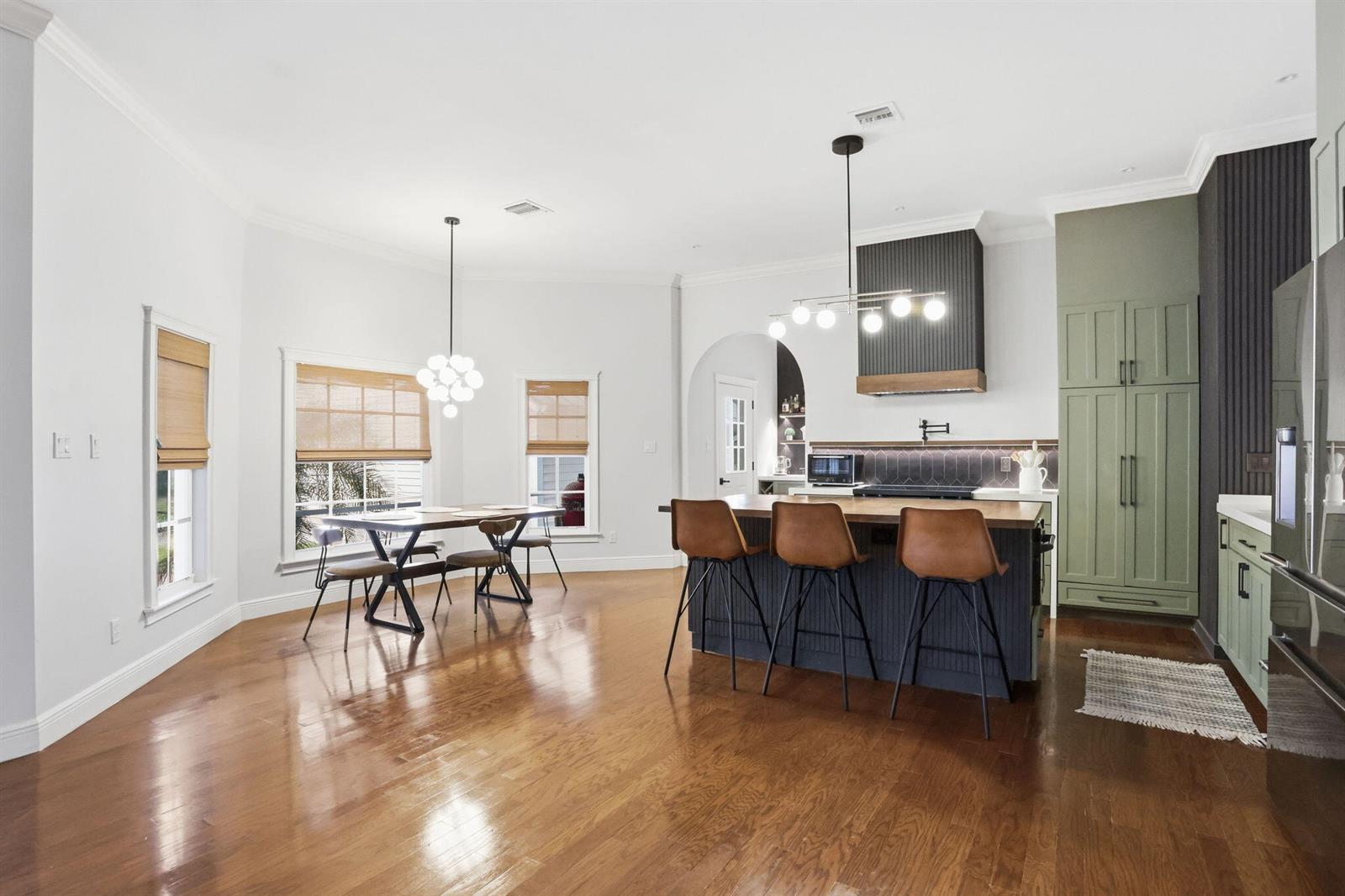 A kitchen and dining area with hardwood floors, a dark island, and sage green cabinetry — 17241 N 123rd Ter Terrace N, FL 33478, FL