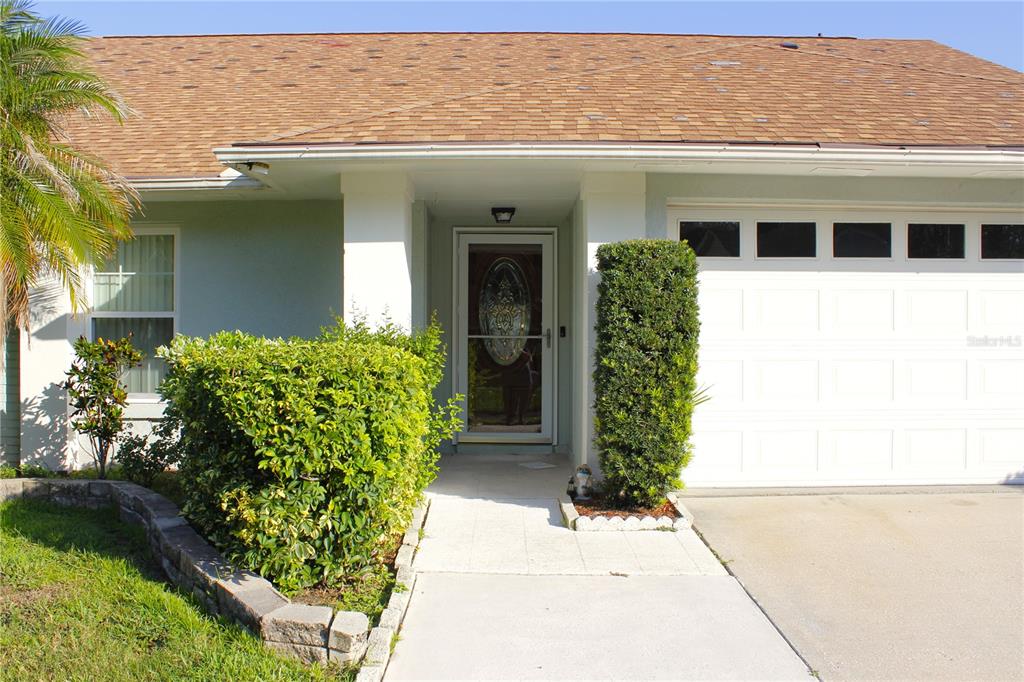 A single-story house exterior features a front door, a garage, and a landscaped yard — 1913 FIRETHORN COURT, BRANDON, FL