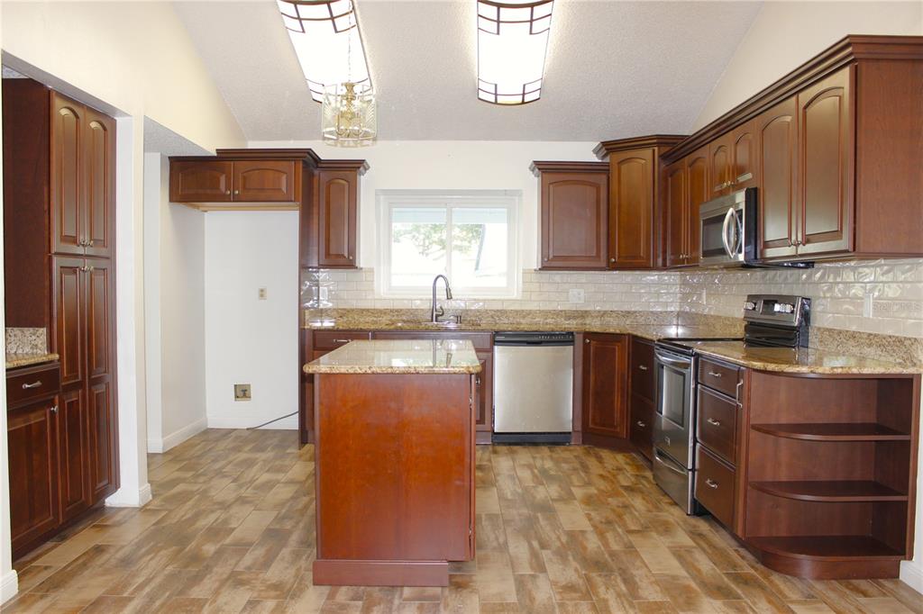 A kitchen with dark wood cabinets, granite countertops, stainless steel appliances, and wood-look tile flooring — 1913 FIRETHORN COURT, BRANDON, FL