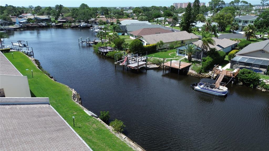 An aerial view shows a canal lined with residential houses, private docks, and a boat — 4533 MARINE PARKWAY UNIT 101, NEW PORT RICHEY, FL