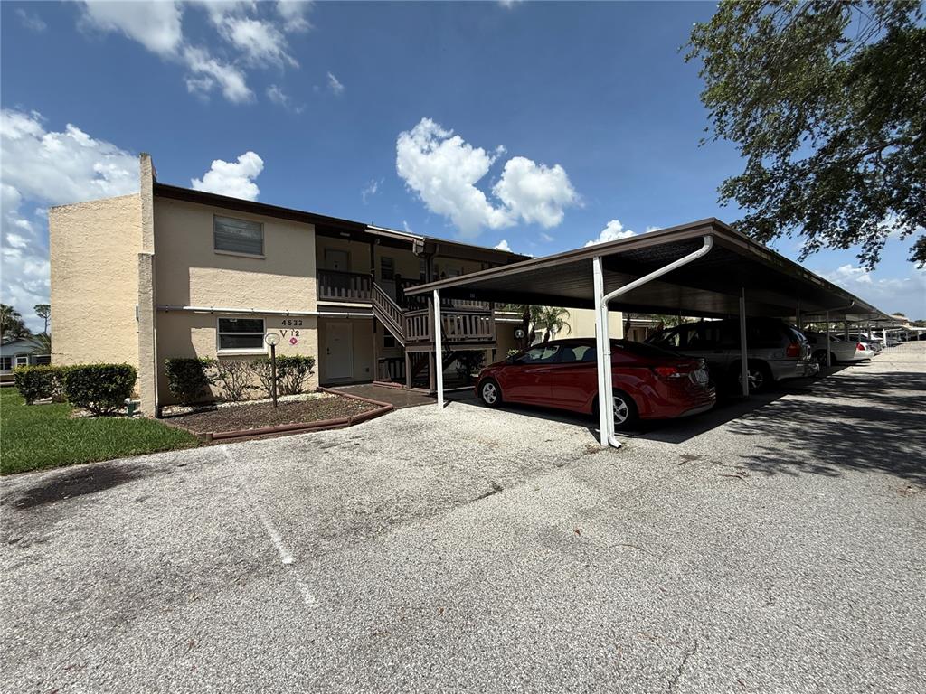 A two-story apartment building with a covered parking area and a red car parked underneath — 4533 MARINE PARKWAY UNIT 101, NEW PORT RICHEY, FL