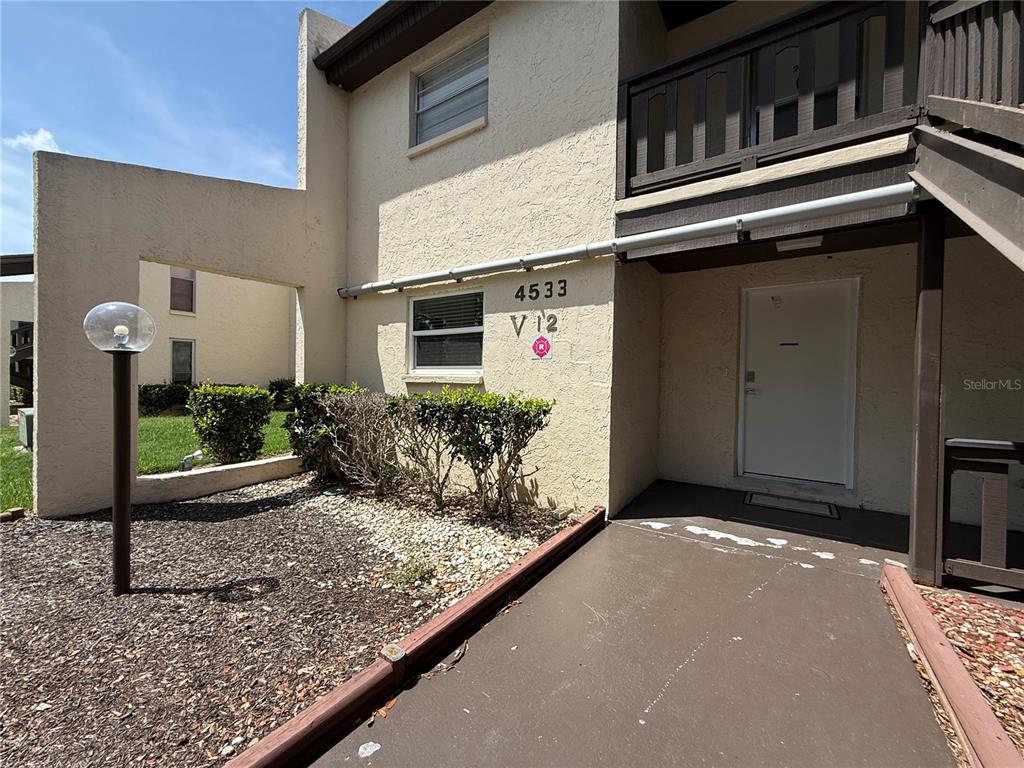 The exterior of a multi-story apartment building features a tan stucco facade and a walkway — 4533 MARINE PARKWAY UNIT 101, NEW PORT RICHEY, FL