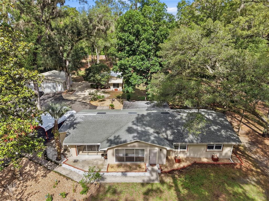 An aerial view shows a single-story house with a gray roof, driveway, and detached garage — 3630 NW 136TH STREET, GAINESVILLE, FL