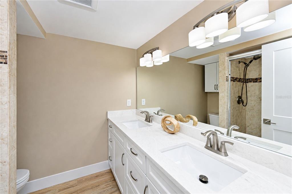A bathroom features a double vanity with white cabinets, stone countertops, and a large mirror — 4857 INDEPENDENCE DRIVE, BRADENTON, FL