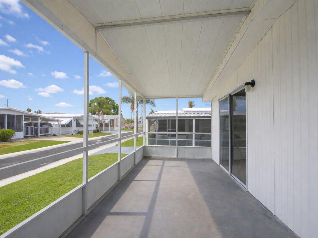 A screened-in porch with a concrete floor and sliding glass doors overlooks a residential street — 4800 SE Federal Highway # 145, Stuart FL 34997, STUART, FL
