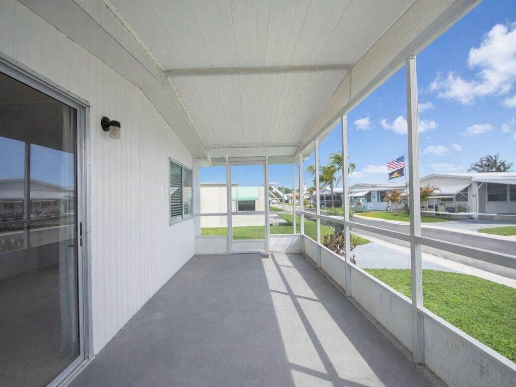 A screened-in porch with a concrete floor, white siding, and views of a neighborhood street — 4800 SE Federal Highway # 145, Stuart FL 34997, STUART, FL