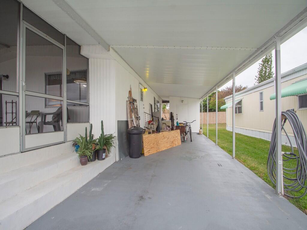 A covered concrete carport runs alongside a home with a screened-in porch and white siding — 4800 SE Federal Highway # 145, Stuart FL 34997, STUART, FL