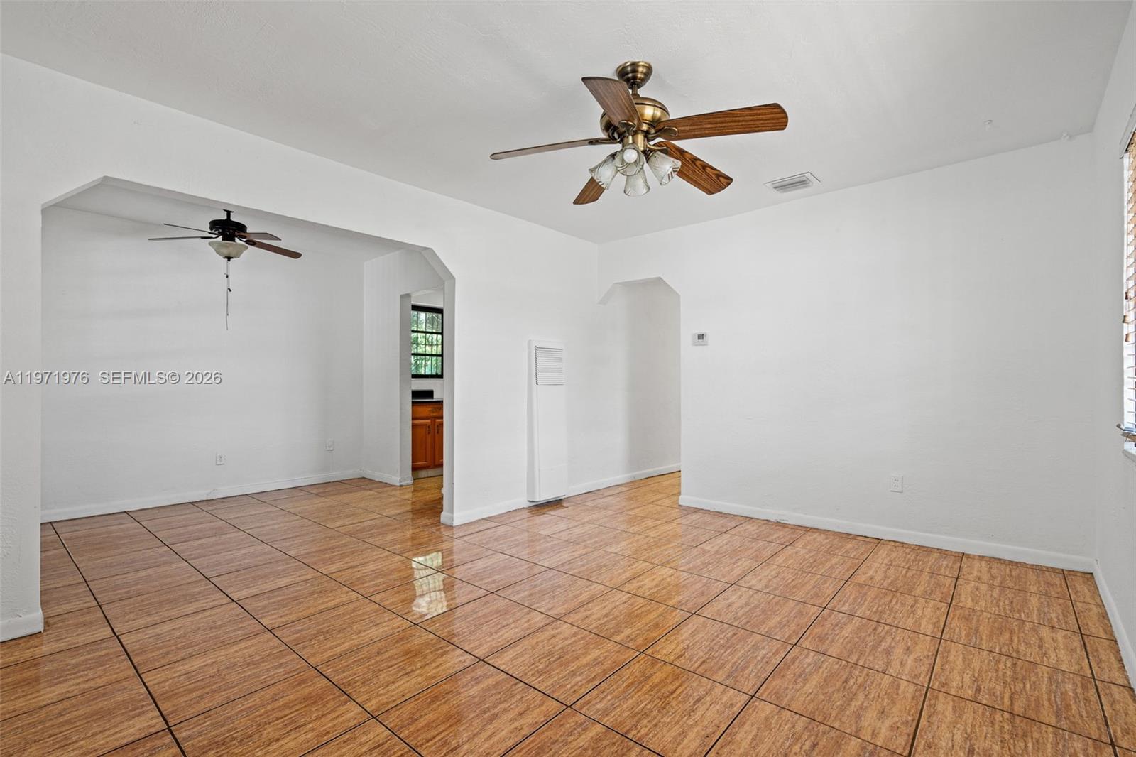 A bright living room features white walls, tiled flooring, and two ceiling fans — 9201 NW 33rd Ave Rd, Miami FL 33147, MIAMI, FL