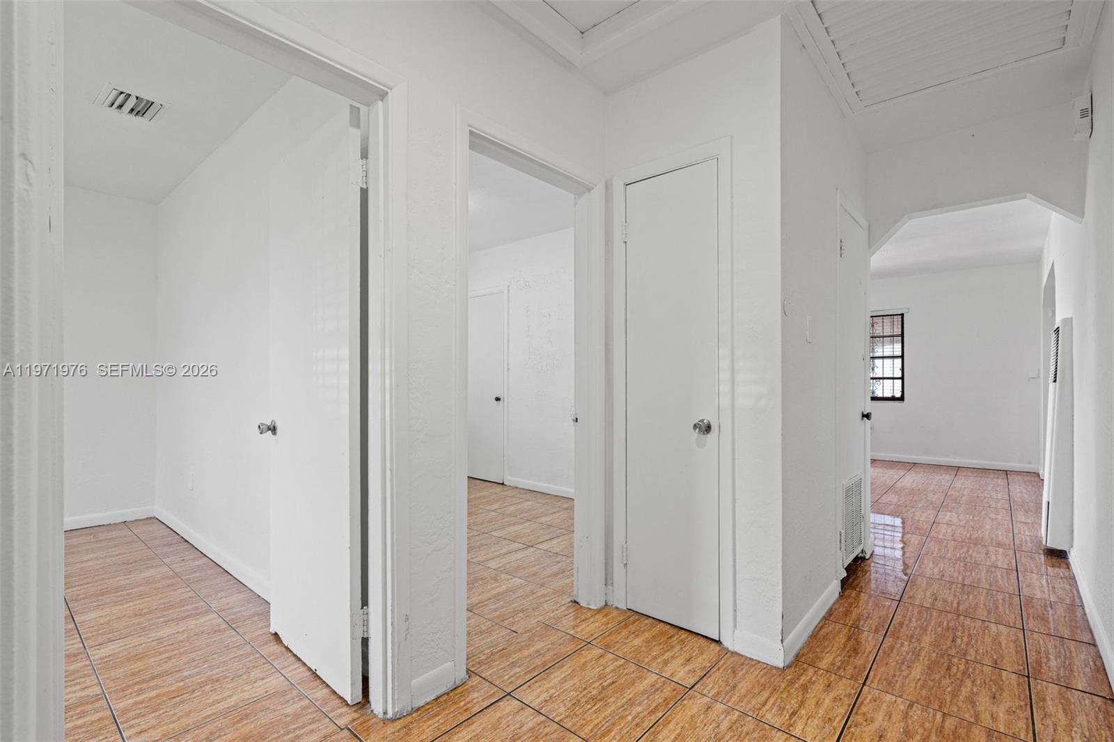 A hallway with white walls, tiled floors, and several closed interior doors — 9201 NW 33rd Ave Rd, Miami FL 33147, MIAMI, FL