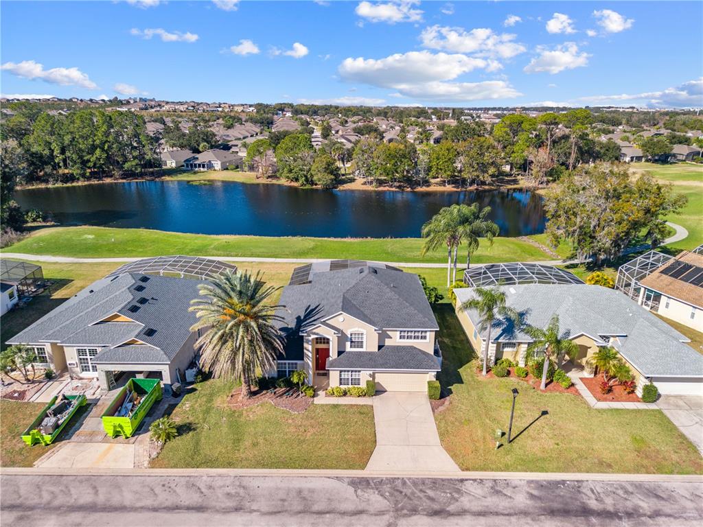 An aerial view shows three suburban houses with screened lanais facing a lake and golf course — 1020 GOLF COURSE PARKWAY, DAVENPORT, FL