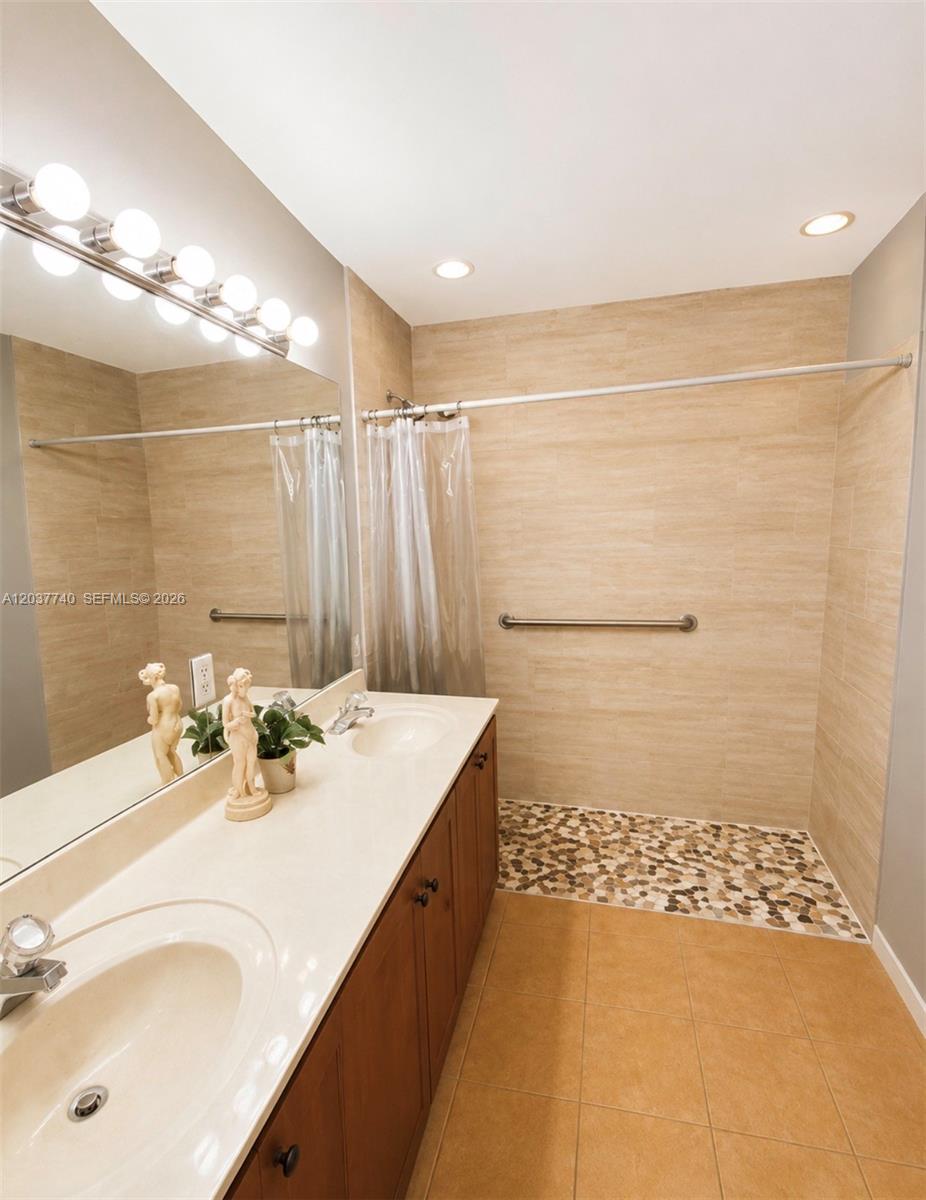 A bathroom features a double vanity, a walk-in shower with pebble flooring, and beige tiles — 16355 SW 46th Ter # 16355, Miami FL 33185, MIAMI, FL
