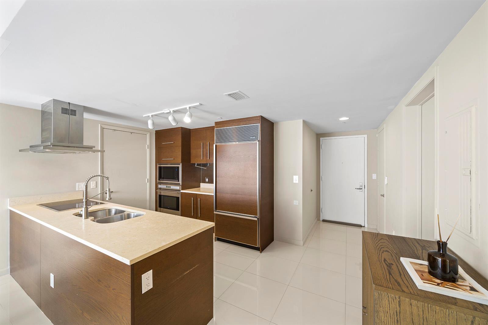 A modern kitchen features dark wood cabinetry, stainless steel appliances, and a stone-topped island — 495 Brickell Avenue # 911, Miami FL 33131, MIAMI, FL