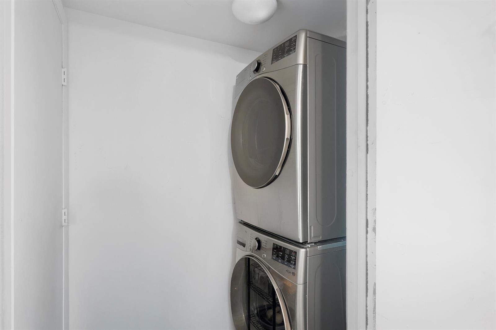 A stacked stainless steel washer and dryer set is installed in a small white closet — 495 Brickell Avenue # 911, Miami FL 33131, MIAMI, FL