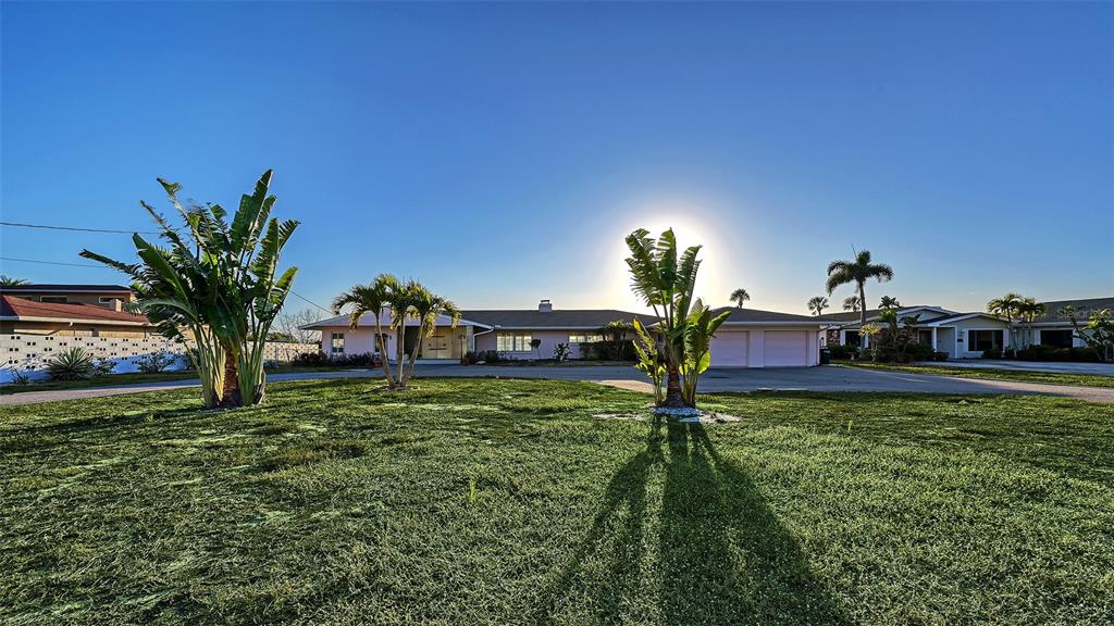 A low-slung, light-pink house with a two-car garage sits behind a large, grassy lawn — 7322 WESTMORELAND DRIVE, SARASOTA, FL