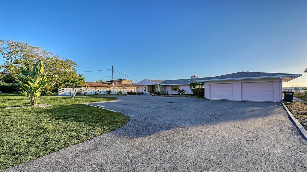 A pink single-story house with a two-car garage sits behind a large paved driveway — 7322 WESTMORELAND DRIVE, SARASOTA, FL