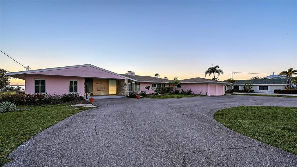 A pink, single-story ranch-style house features a large asphalt driveway and a two-car garage — 7322 WESTMORELAND DRIVE, SARASOTA, FL