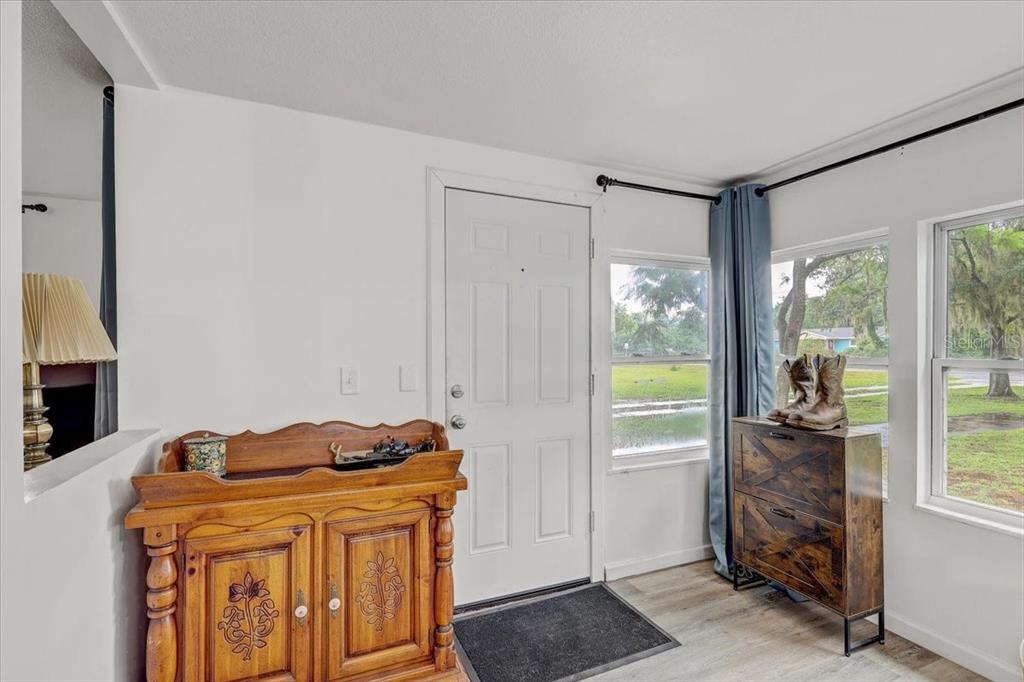 An entryway features a white front door, wood-toned furniture, and windows looking out onto grass — 2557 K VILLE AVENUE, AUBURNDALE, FL