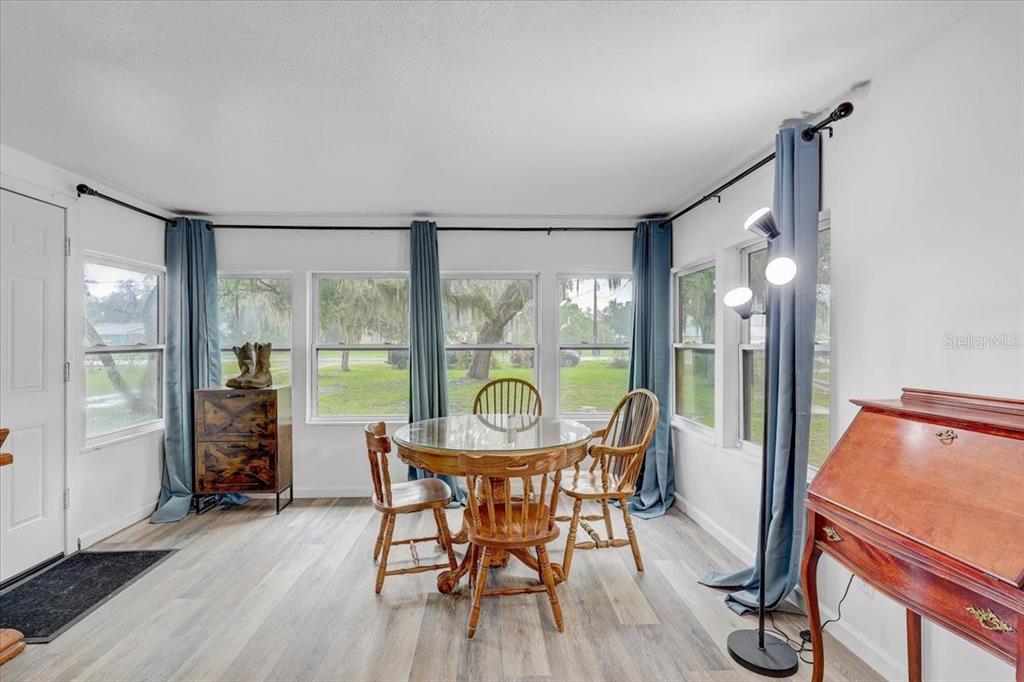 A dining area features a glass-topped wooden table, chairs, blue curtains, and wood-look flooring — 2557 K VILLE AVENUE, AUBURNDALE, FL