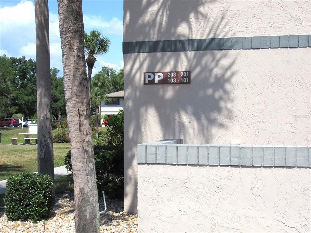 A beige stucco building exterior features a sign labeled PP with unit numbers 101-203 — 19505 QUESADA AVENUE UNIT PP101, PORT CHARLOTTE, FL