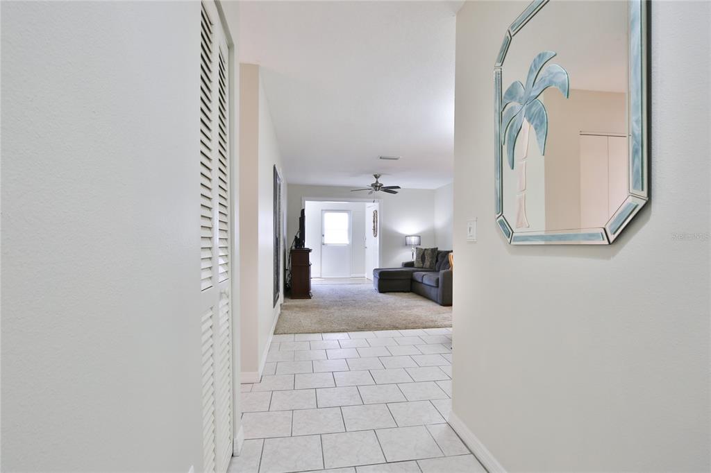 A tiled entryway leads into a carpeted living room with a sofa and ceiling fan — 4612 PARK ACRES DRIVE, BRADENTON, FL