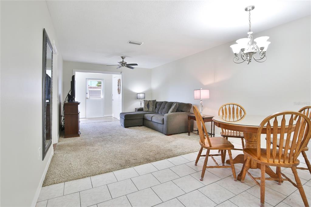 A living room with carpet, a gray sectional sofa, and an adjacent dining area — 4612 PARK ACRES DRIVE, BRADENTON, FL