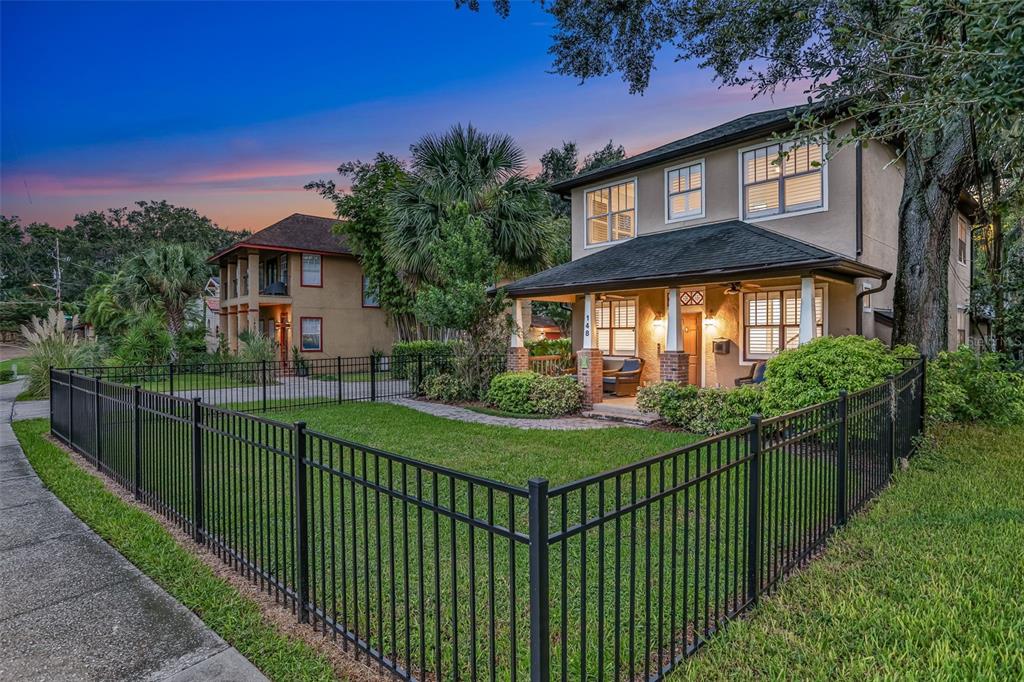 A two-story house with a front porch and black metal fencing in the front yard — 148 S THORNTON AVENUE, ORLANDO, FL