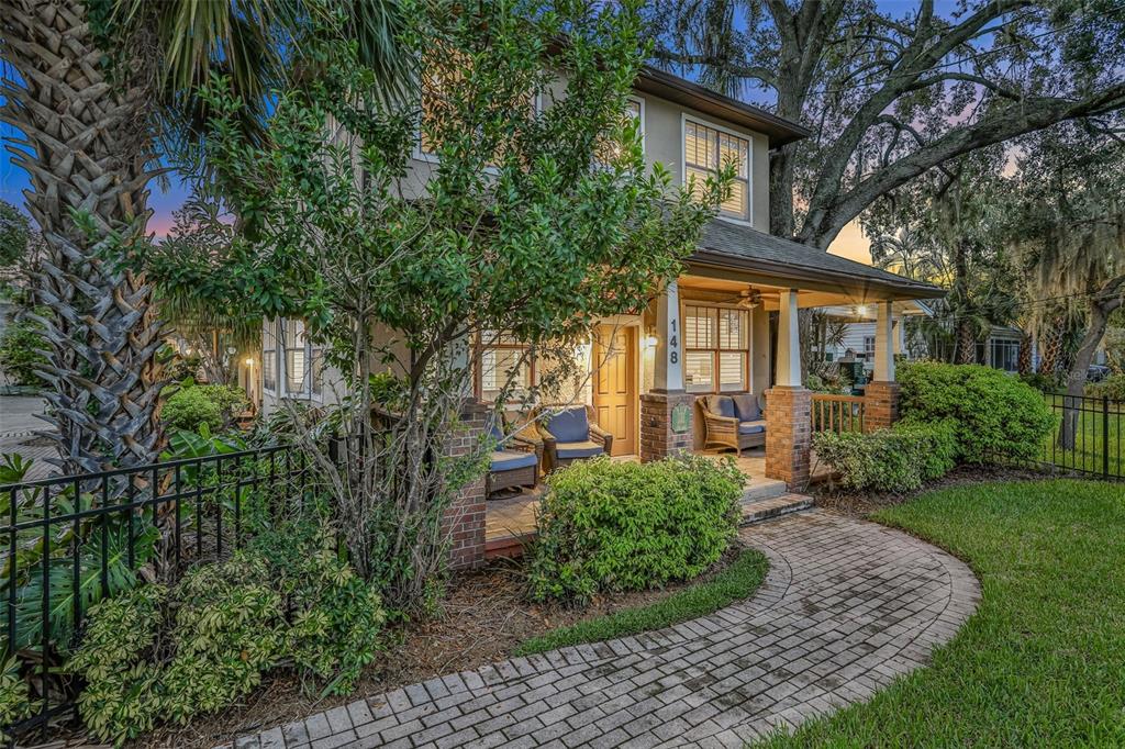 A two-story house with a brick-columned front porch and a paved walkway through the yard — 148 S THORNTON AVENUE, ORLANDO, FL