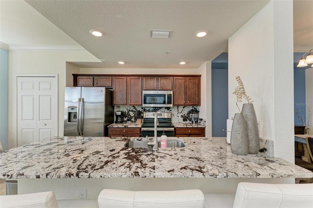 A kitchen features dark wood cabinets, stainless steel appliances, and a large granite-topped island — 16814 VARDON TERRACE UNIT 103, BRADENTON, FL