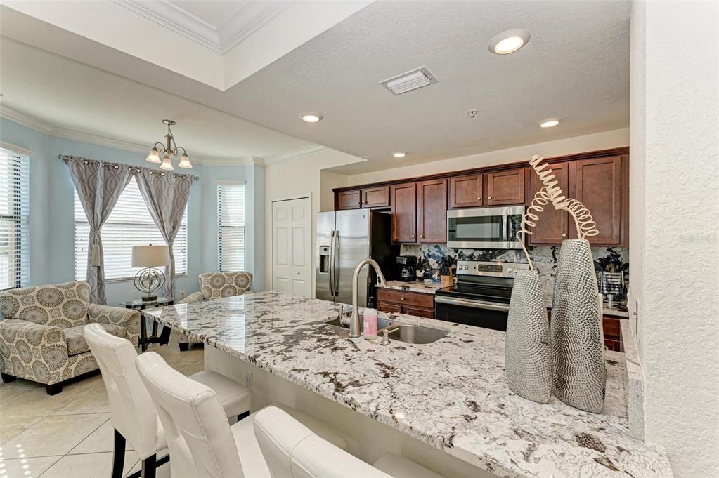 A kitchen with granite countertops, stainless steel appliances, and dark wood cabinets — 16814 VARDON TERRACE UNIT 103, BRADENTON, FL