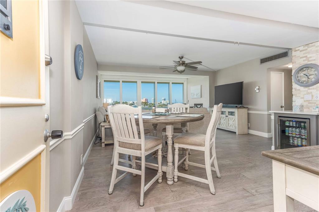 A dining area with a round wooden table, white chairs, and a view of buildings — 31 ISLAND WAY UNIT 409, CLEARWATER BEACH, FL