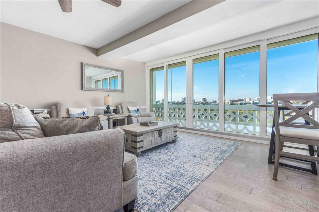 A living room with light gray furniture, a patterned rug, and large windows overlooking a city — 31 ISLAND WAY UNIT 409, CLEARWATER BEACH, FL