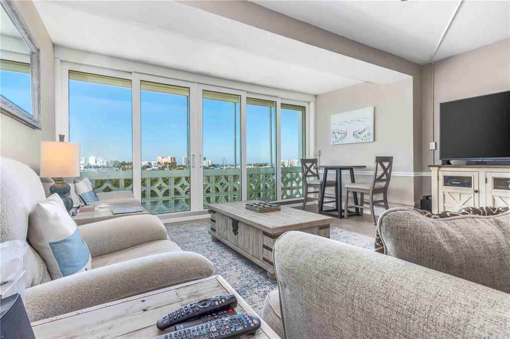 A living room features a sliding glass door balcony, neutral furniture, and a dining set — 31 ISLAND WAY UNIT 409, CLEARWATER BEACH, FL