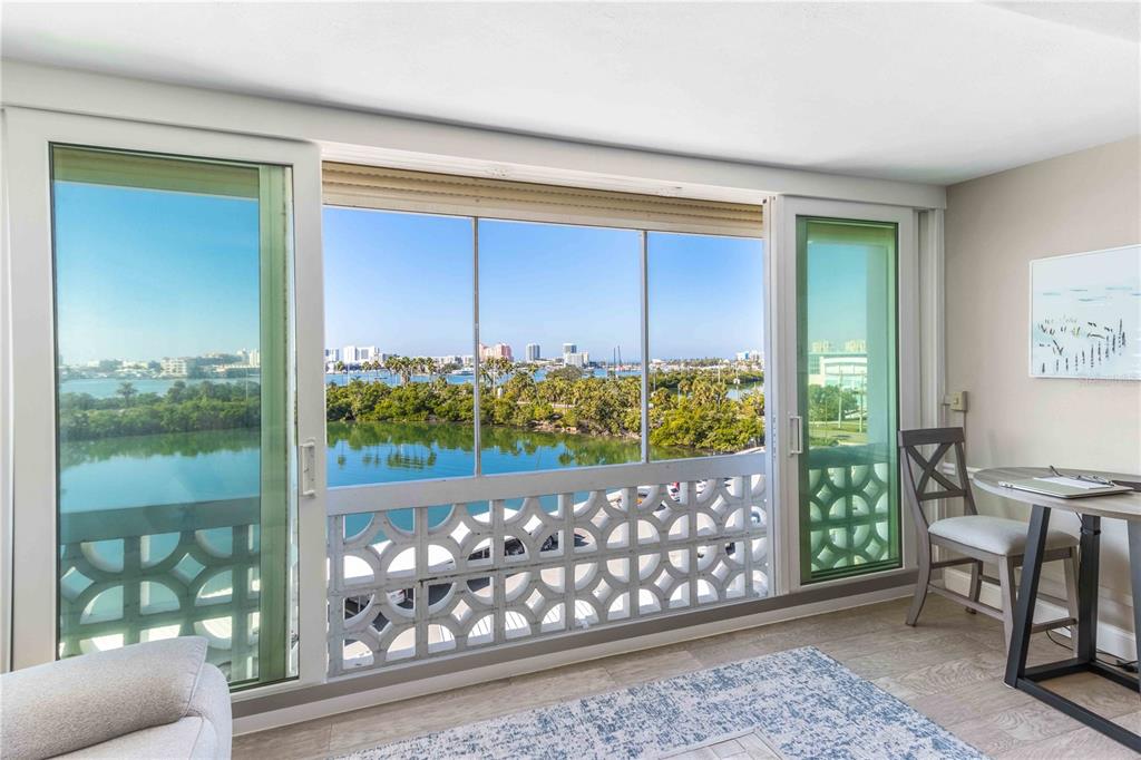 A room with large sliding glass doors overlooking a body of water and city skyline — 31 ISLAND WAY UNIT 409, CLEARWATER BEACH, FL