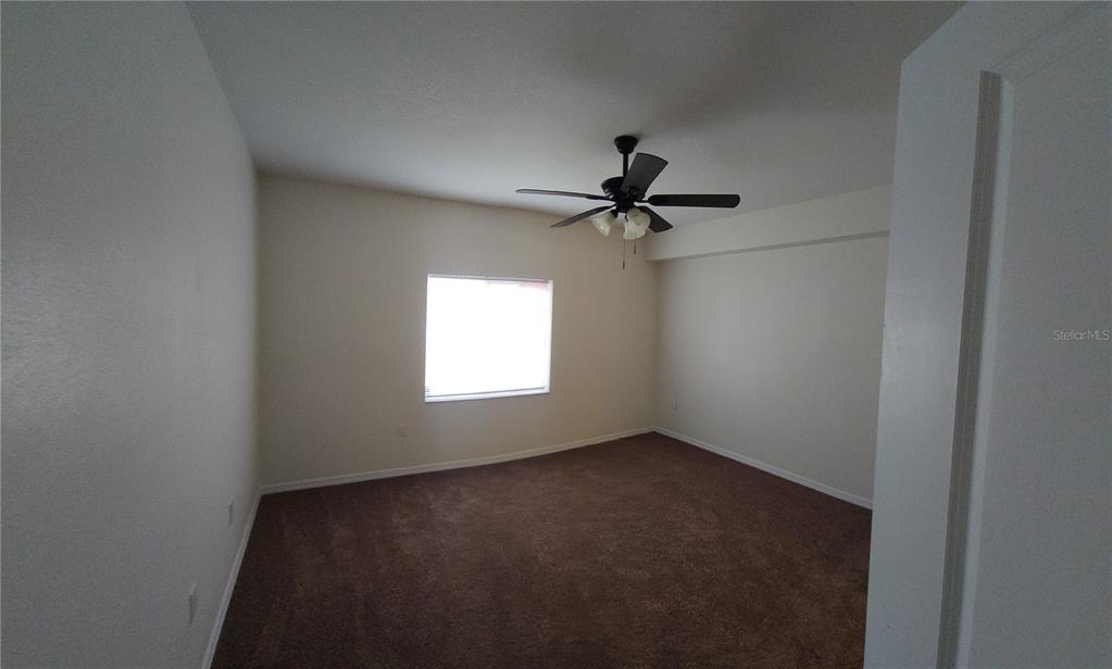 An empty bedroom features beige walls, brown carpeting, and a ceiling fan — 9515 GROVEDALE CIRCLE UNIT 101, RIVERVIEW, FL