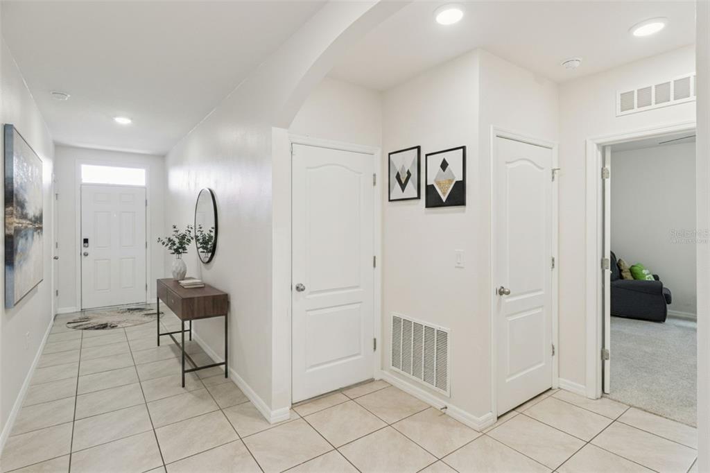 A bright entryway features tiled floors, a console table, two closed doors, and wall art — 4013 SILVERSTREAM TERRACE, SANFORD, FL