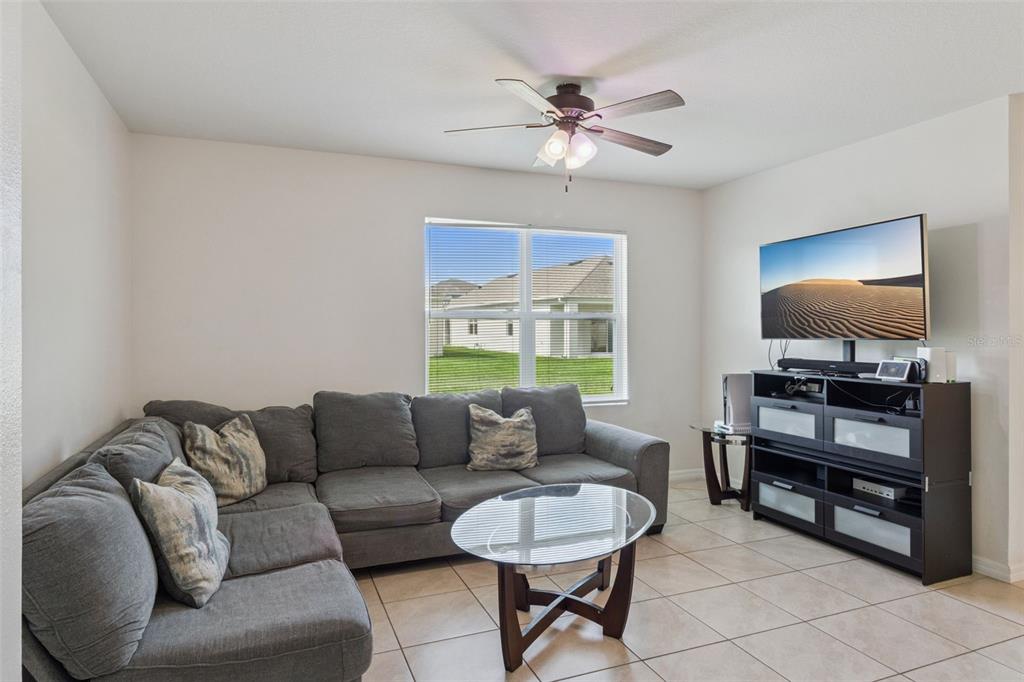 A living room features a gray sectional sofa, a glass coffee table, and a television console — 4013 SILVERSTREAM TERRACE, SANFORD, FL