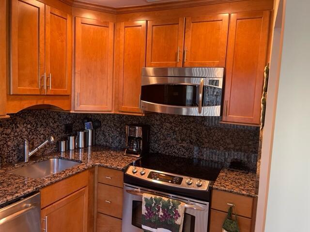 A kitchen features wood cabinets, granite countertops, a stainless steel microwave, and a range — 22 Colonial Club Drive # 103, Boynton Beach FL 33435, BOYNTON BEACH, FL