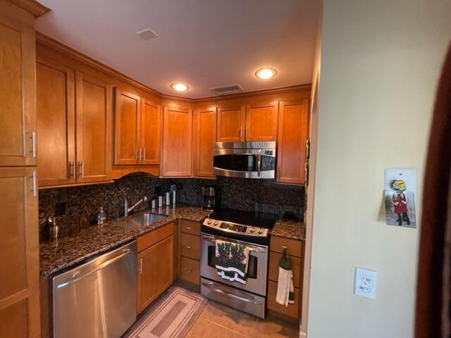 A kitchen features wood cabinets, granite countertops, and stainless steel appliances — 22 Colonial Club Drive # 103, Boynton Beach FL 33435, BOYNTON BEACH, FL