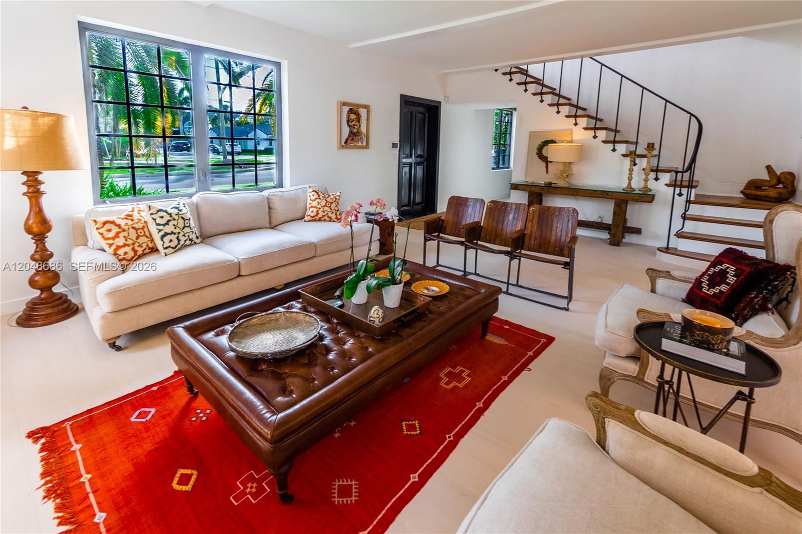 A living room features a tufted leather ottoman, a red rug, and a staircase — 255 PALM AVENUE, Miami Beach FL 33139, MIAMI BEACH, FL