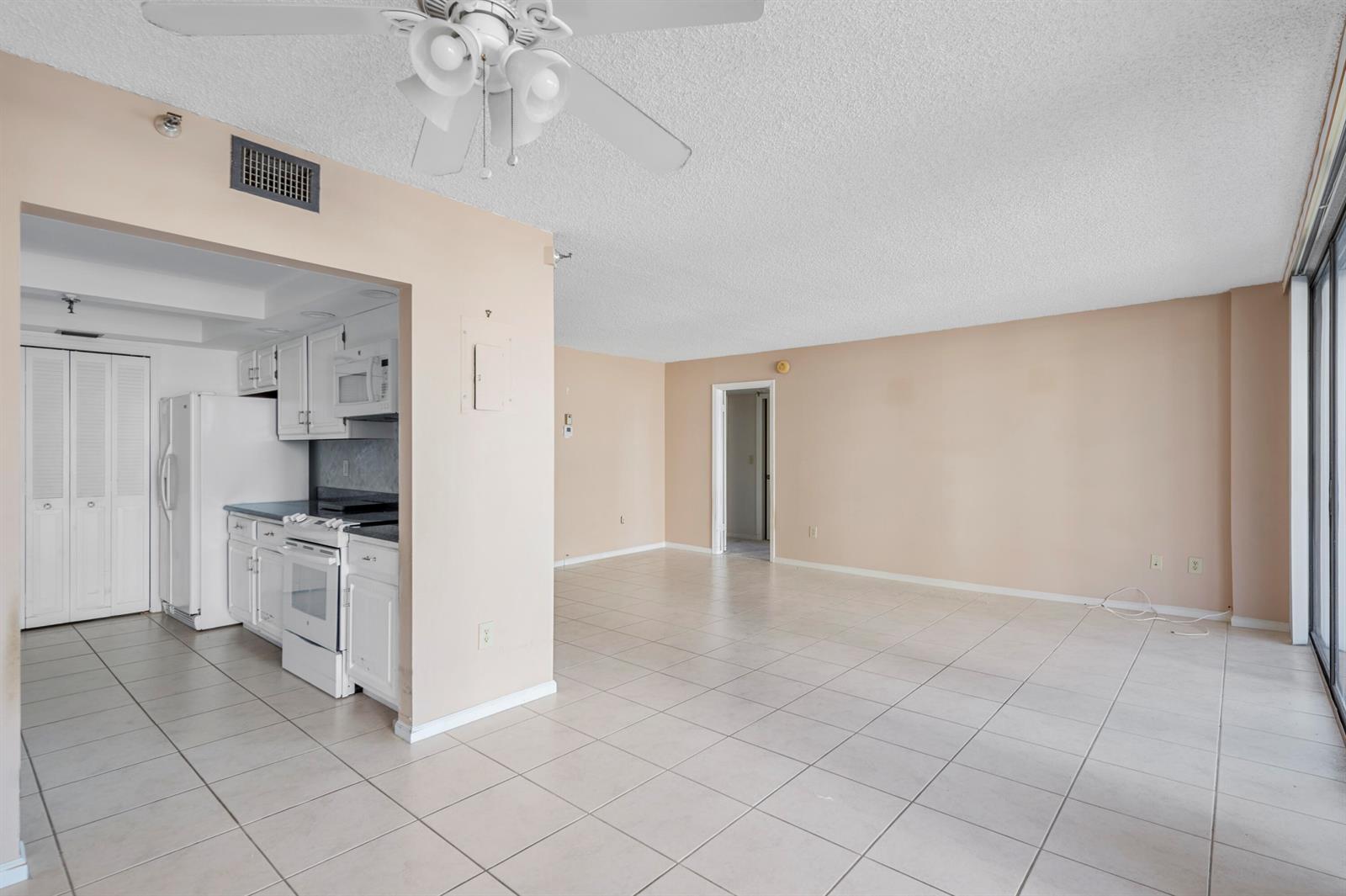 An open-concept living area with tile flooring, a ceiling fan, and an adjacent white kitchen — 859 Jeffery Street # 312, Boca Raton FL 33487, BOCA RATON, FL