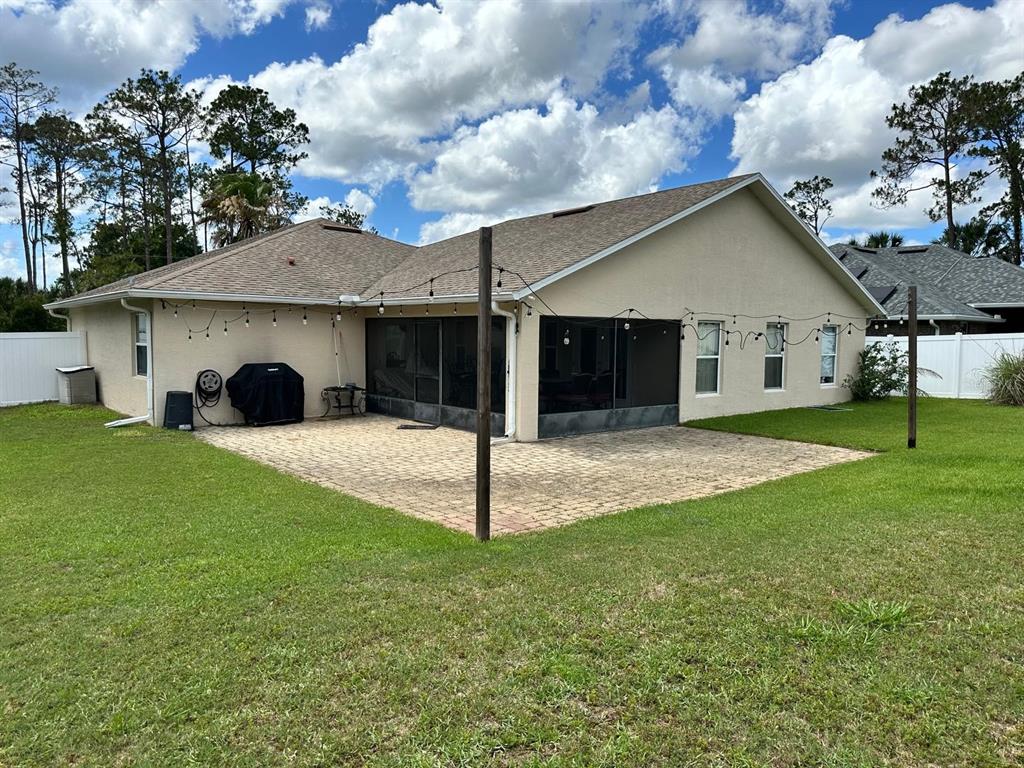 A beige house with a screened-in porch and a paved patio in the backyard — 9 RANBER PLACE, PALM COAST, FL