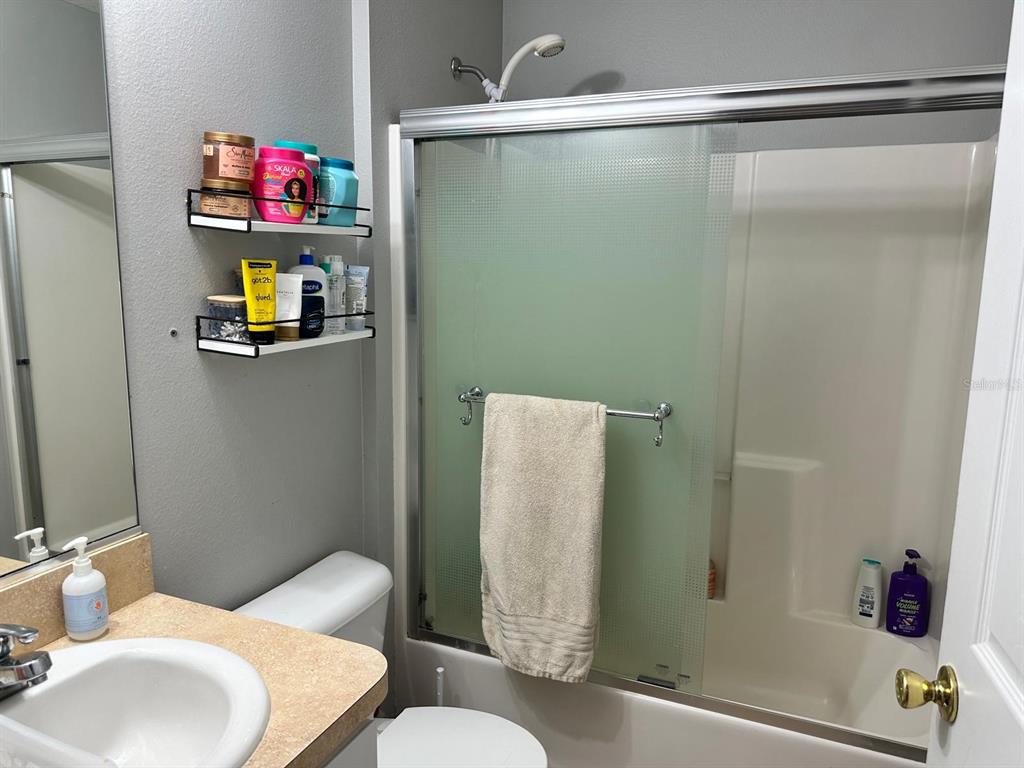 A bathroom features a vanity with a sink, two wall-mounted shelves, and a shower-tub combo — 9 RANBER PLACE, PALM COAST, FL