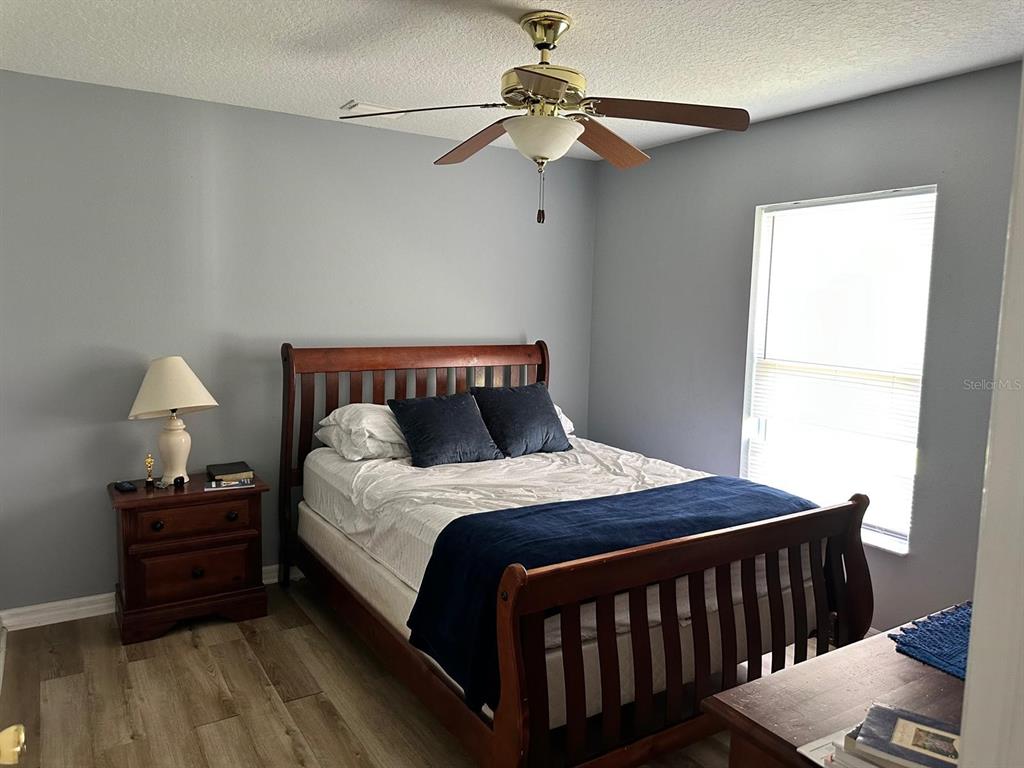 A bedroom features a wooden bed frame, a nightstand with a lamp, and wood-look flooring — 9 RANBER PLACE, PALM COAST, FL