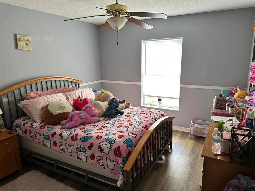 A bedroom features a bed with a Hello Kitty comforter, wood-look flooring, and a ceiling fan — 9 RANBER PLACE, PALM COAST, FL