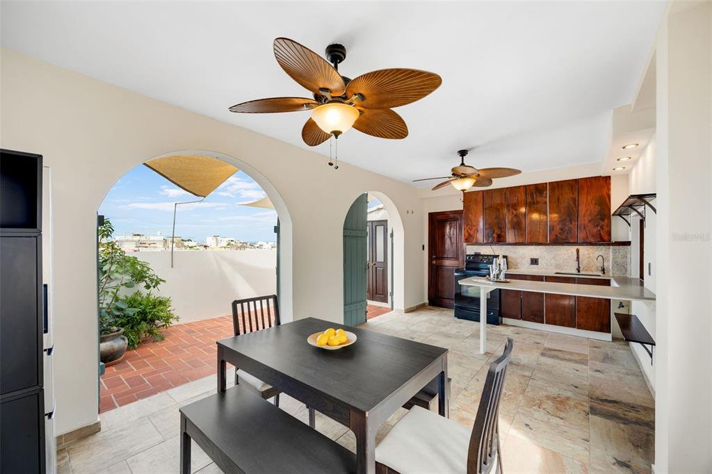 A kitchen and dining area with dark wood cabinets, tile floors, and an arched patio entrance — 152 RAFAEL CORDERO UNIT PH-2, SAN JUAN, PR