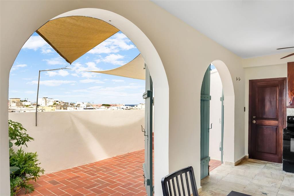 An indoor dining area opens through arched doorways to a tiled terrace with a shade sail — 152 RAFAEL CORDERO UNIT PH-2, SAN JUAN, PR