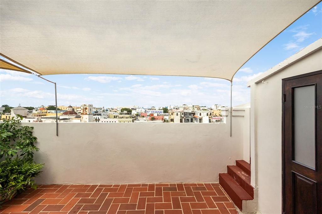 A rooftop terrace with terracotta tile flooring, a shade sail, and a city view — 152 RAFAEL CORDERO UNIT PH-2, SAN JUAN, PR