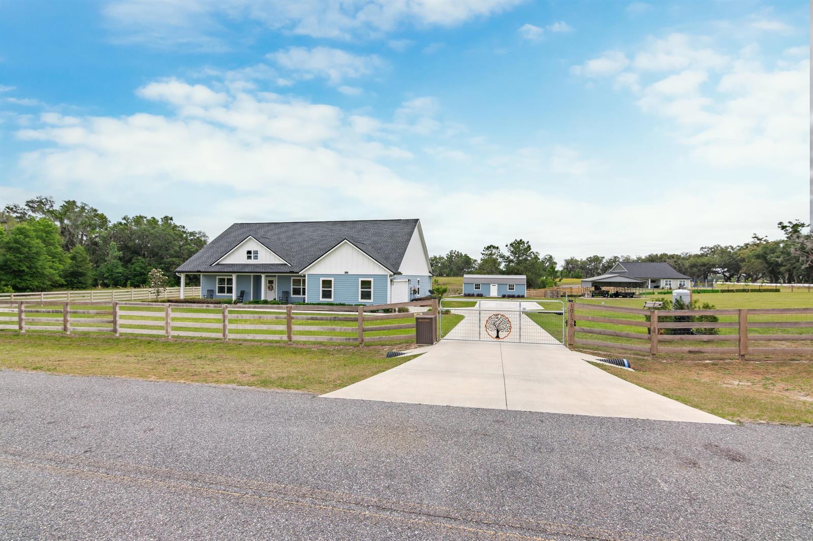 A blue house with a white trim and a fenced yard sits behind a gated driveway — 10172 98th Path, FL 32060, FL