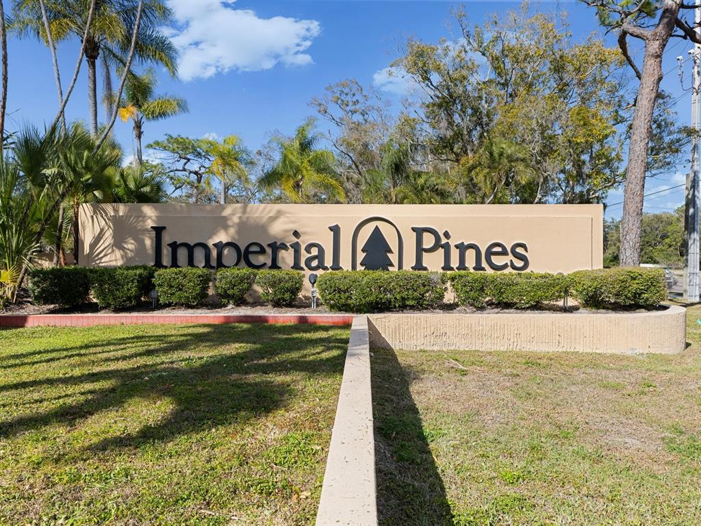 A beige monument sign for Imperial Pines stands in front of trees and landscaping — 3076 EASTLAND BOULEVARD UNIT 210, CLEARWATER, FL